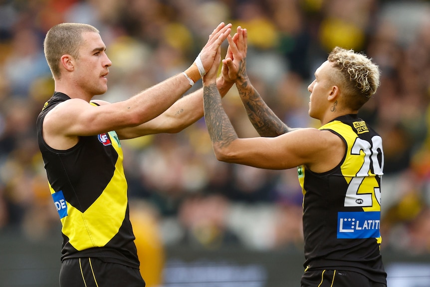 Two Richmond AFL players celebrate a goal against West Coast Eagles.