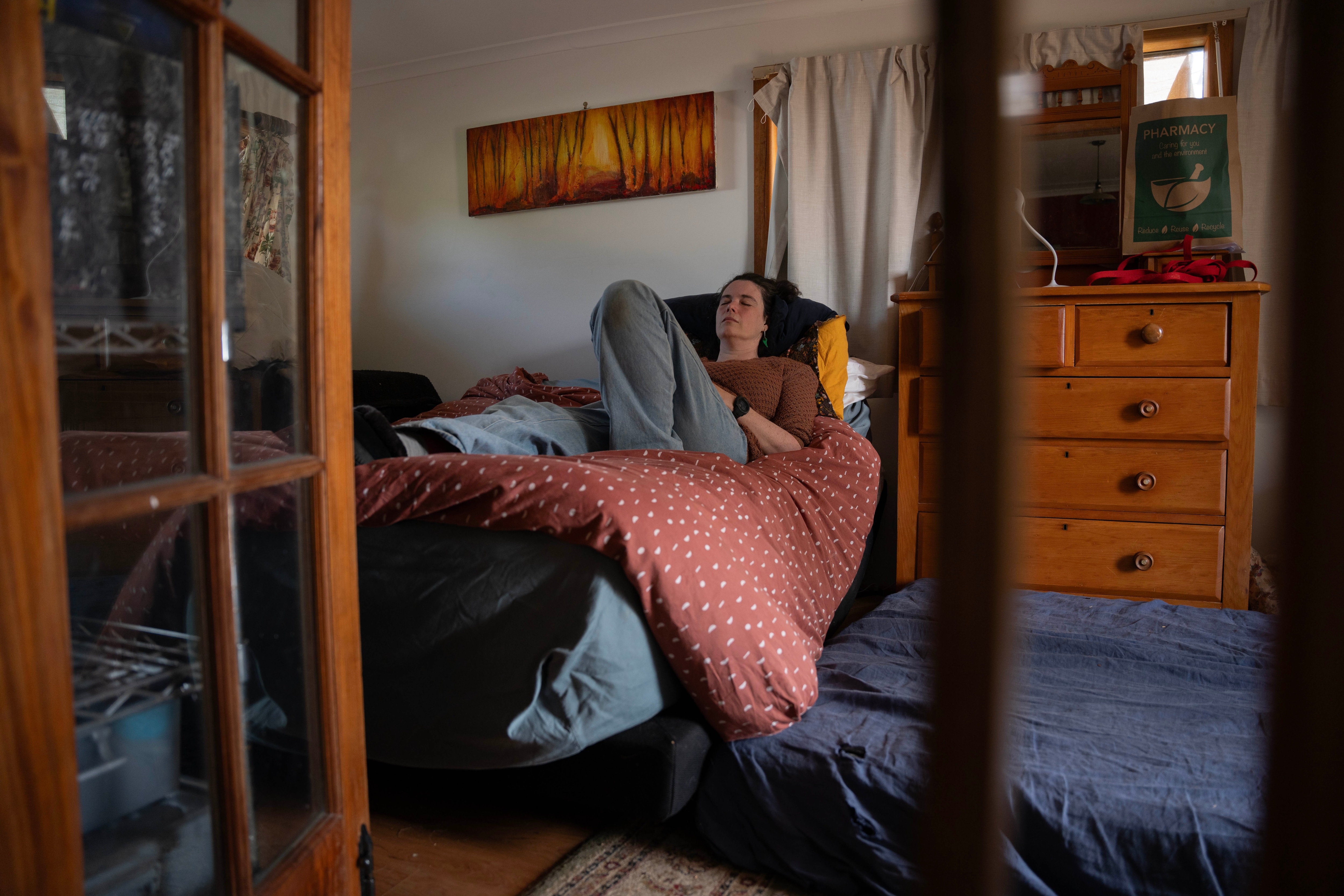 A lady lays down in bed with her eyes closed.