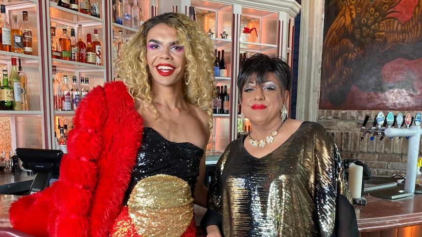 Two Indigenous transgender people standing in a bar.