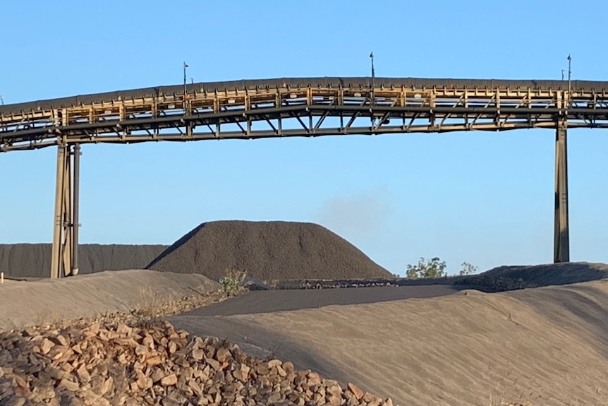 Mounds of manganese ore, with a conveyor bridge used to load it onto ships.