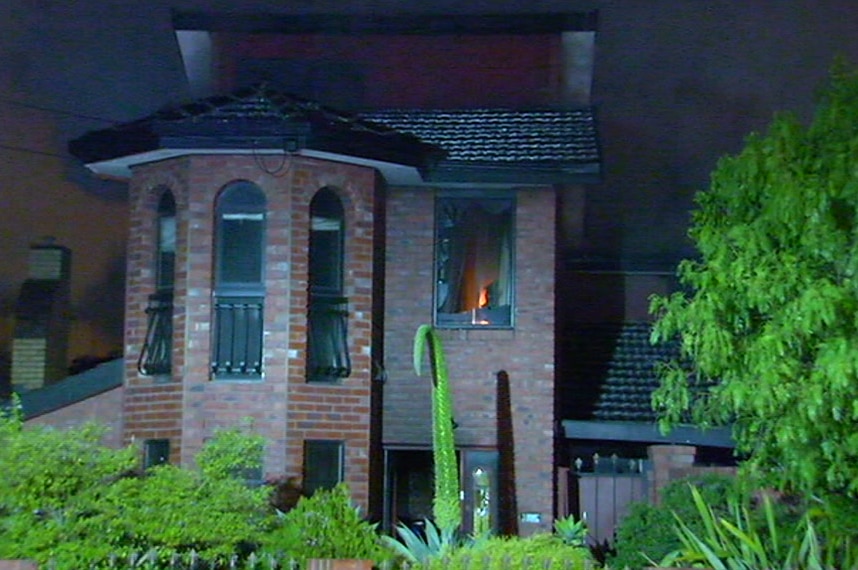 A fire burns as a broken window can be seen in a double storey house on fire in West Footscray.