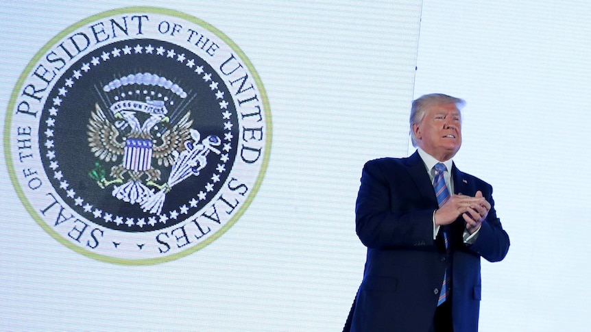 US President Donald Trump takes the stage next to an altered presidential seal prior.