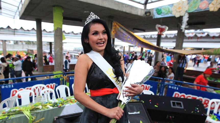 Tatiana Noguera holds flowers wrapped in silver and wears her crown after winning the pageant