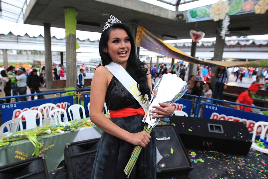 Tatiana Noguera holds flowers wrapped in silver and wears her crown after winning the pageant