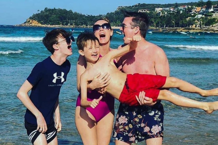 A happy family photo of four people on a beach