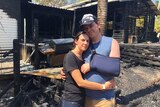 Holly and David Kemp hug at the bushfire-destroyed remains of their home.