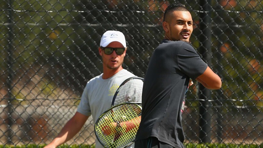 Watchful eye ... Lleyton Hewitt (background) keeps track of Nick Kyrgios during a practice session at Kooyong