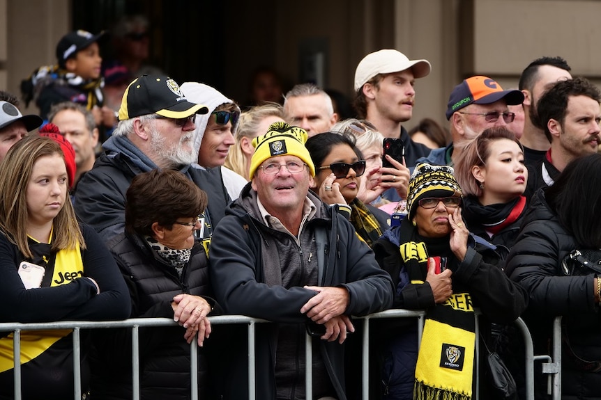 A group of AFL fans wearing Richmond Tigers merchandise look on as the grand final parade takes place.