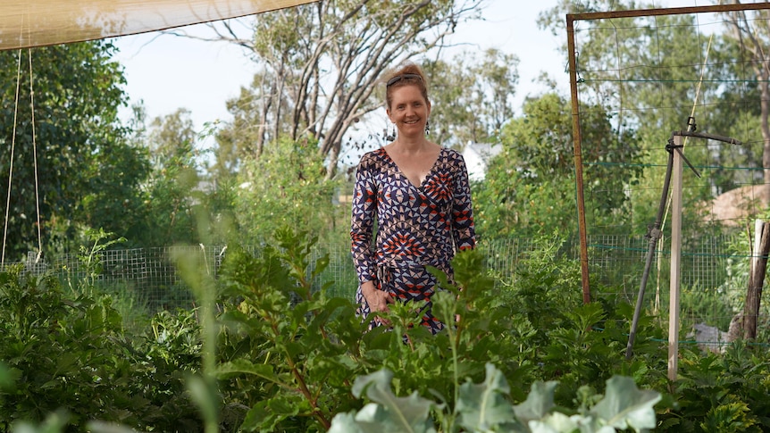 A woman stands in the middle of a green food garden