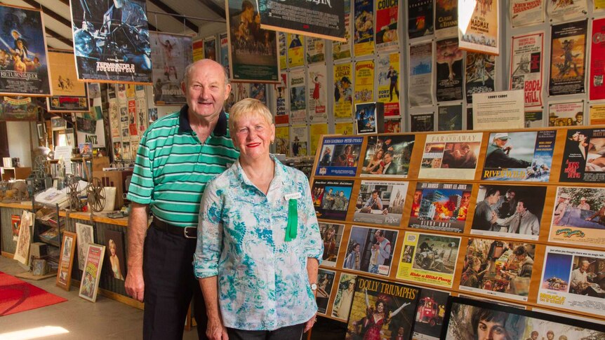 Man and woman standing in front of poster museum collection at Manildra, NSW.
