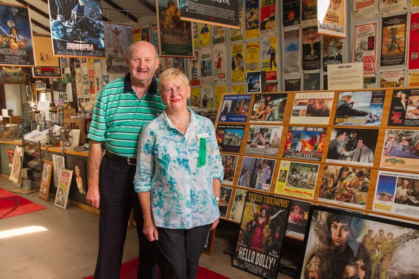 Man and woman standing in front of poster museum collection at Manildra, NSW.