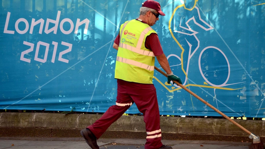 A municipal worker cleans a street before the start of the London Olympics.