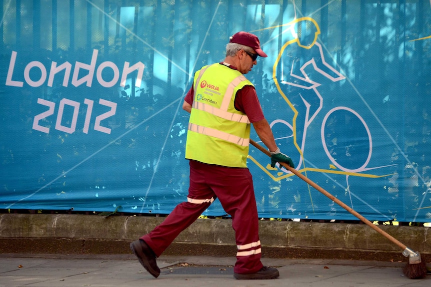 A municipal worker cleans a street before the start of the London Olympics.