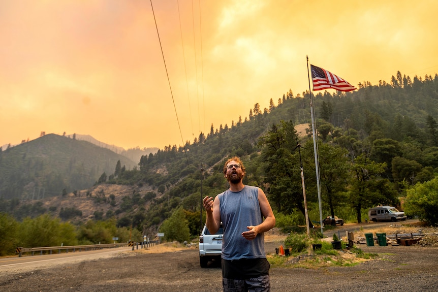 Benjamin Bell osserva un Dixie Fire bruciare lungo la Interstate 70 nella foresta nazionale di Plumas, in California.