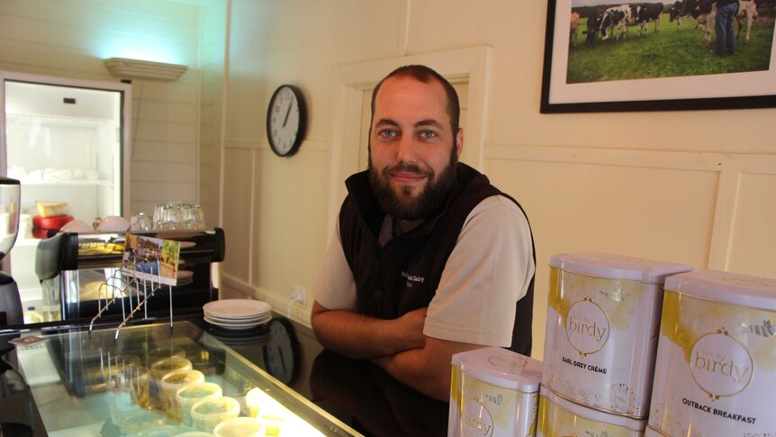 Young farmer Simon Schultz standing in front of a cheese case in a cafe on his family's dairy farm