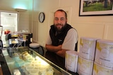 Young farmer Simon Schultz standing in front of a cheese case in a cafe on his family's dairy farm