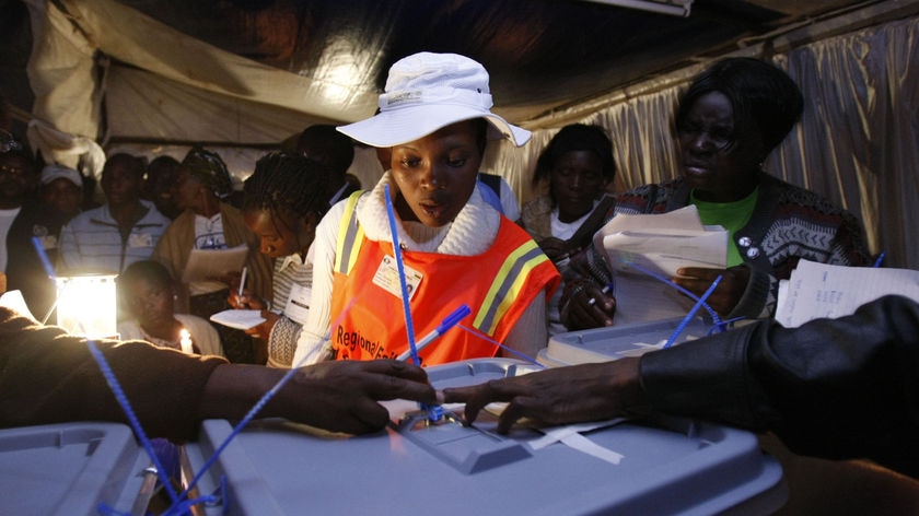 A Zimbabwe election observer checks the seal on ballot boxes at the end of polling in Harare