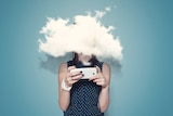 Young woman using phone with head in the clouds.