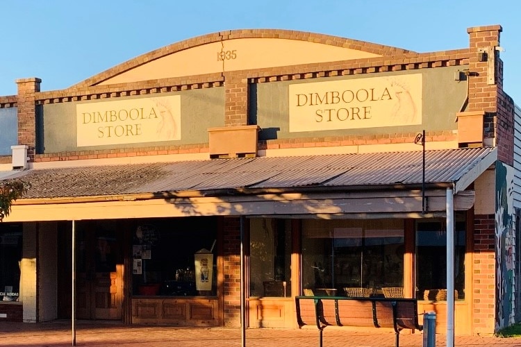 A bricks and mortar store with awnings glows yellow in the setting sun.