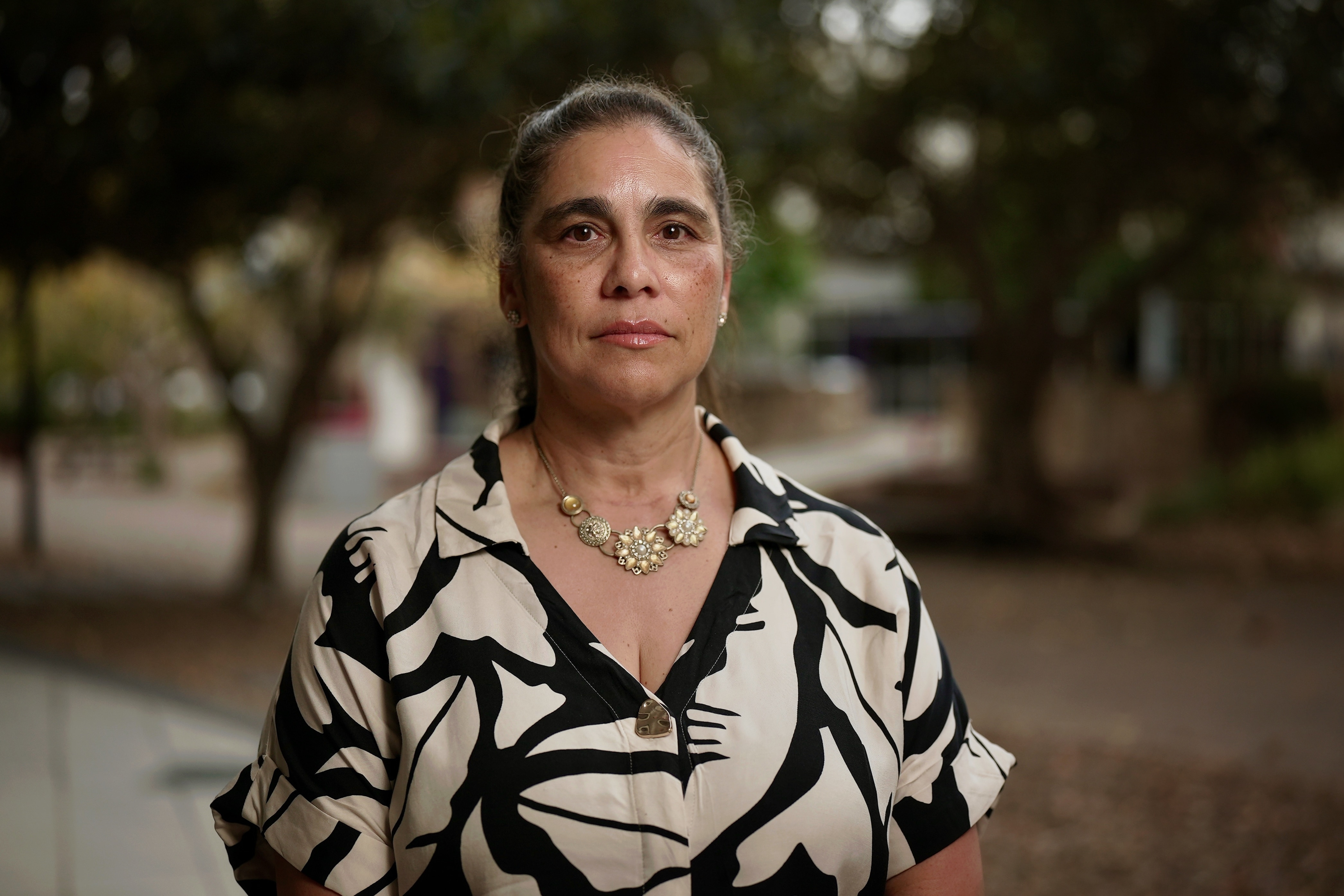 woman with her hair tied up and a black and white shirt on pictured on a university campus