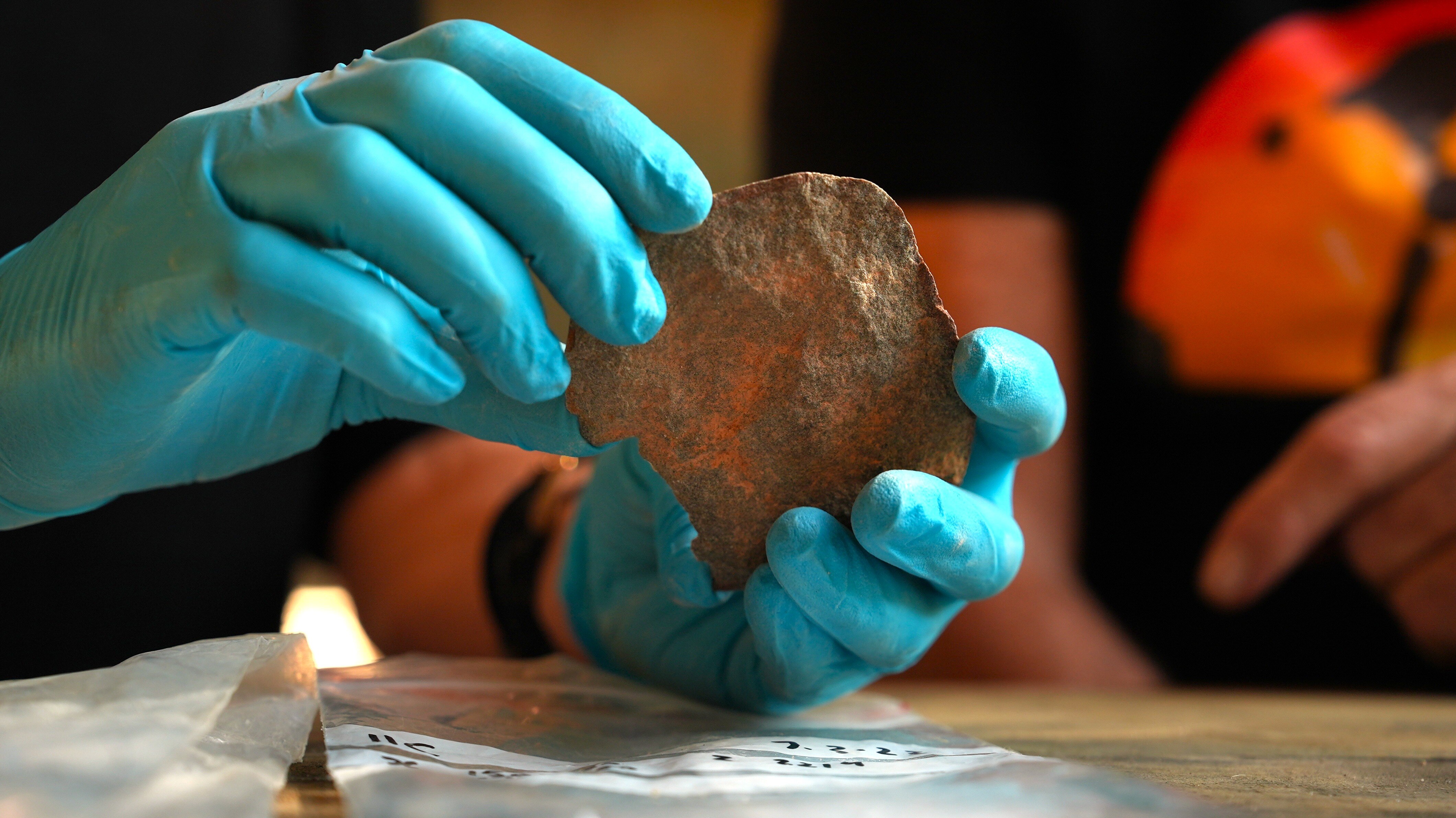 Gloved hands hold a stone.