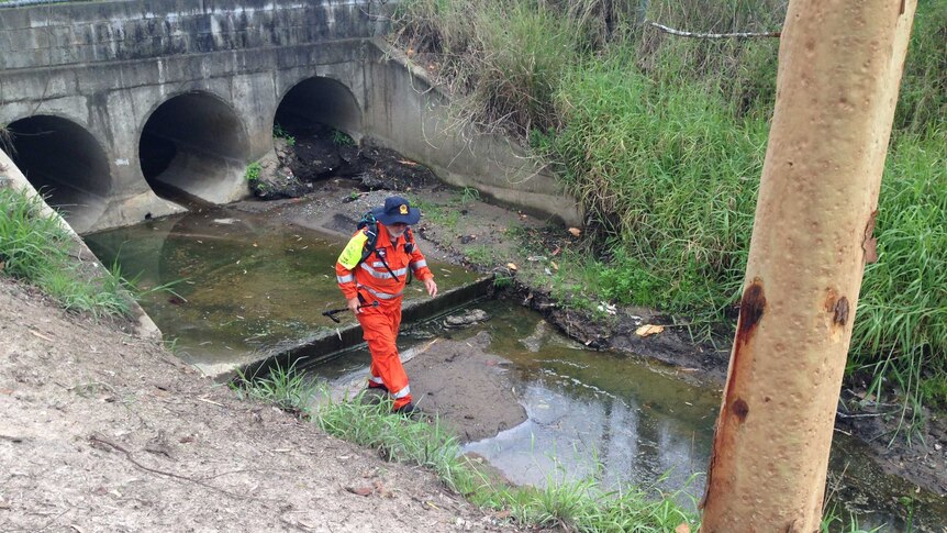 An SES volunteer searches a drain in scrub off Chambers Flat Road at Marsden.