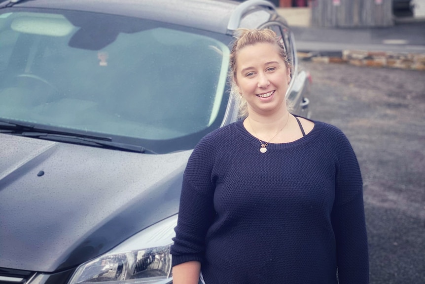 Young woman stand with car in background 