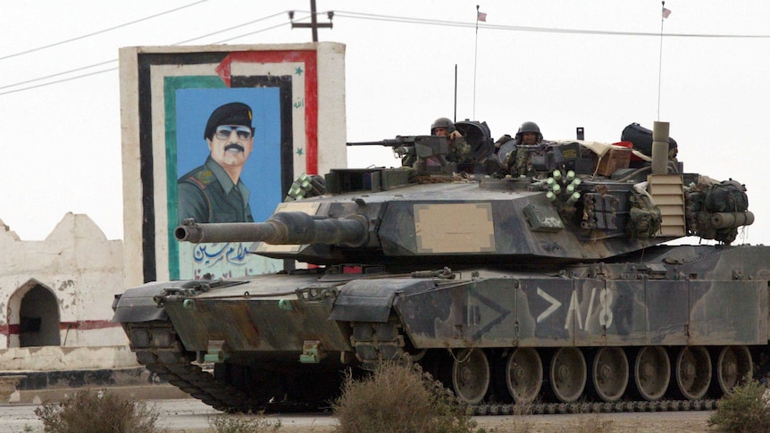 Archival image of a US marine tank in front of a painting of Saddam Hussein March 24, 2003.