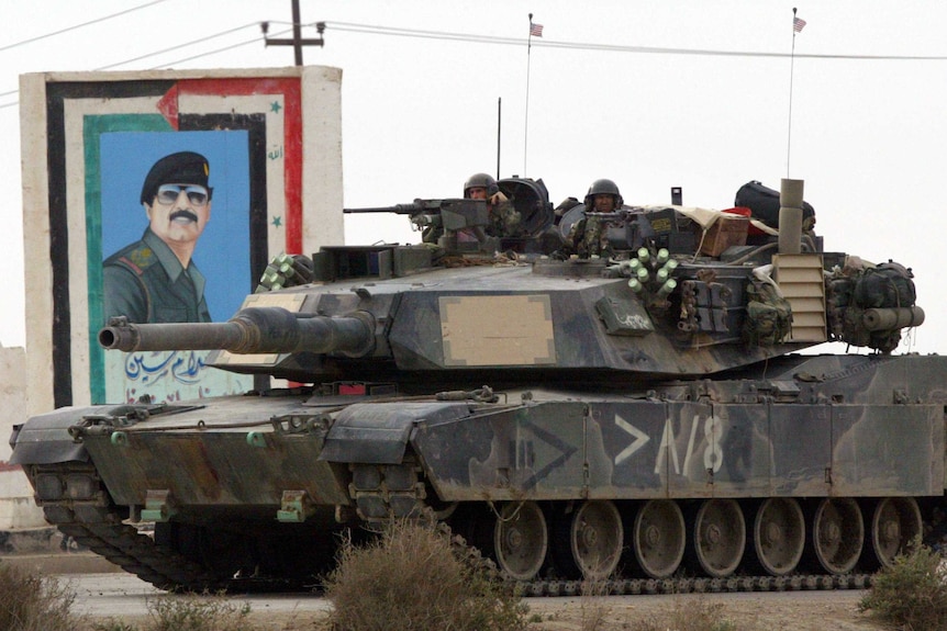 Archival image of a US marine tank in front of a painting of Saddam Hussein March 24, 2003.