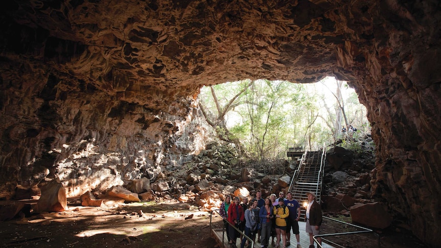 The Arch lava tube shows a cave with a tour group exploring the unique rock formations.