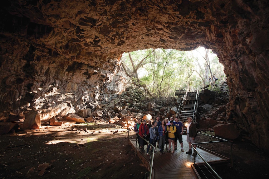 The Arch lava tube shows a cave with a tour group exploring the unique rock formations.