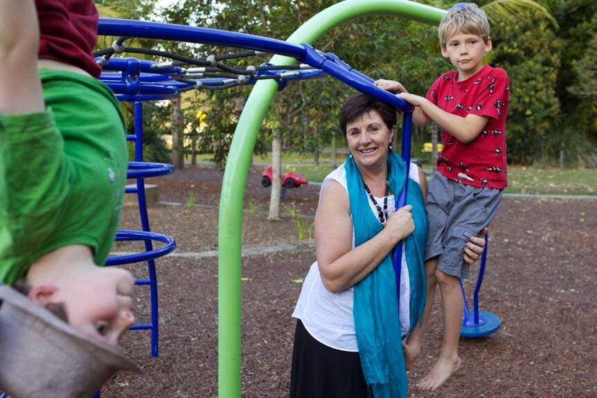 Maggie Dent at a playground with two boys climbing on play equipment.