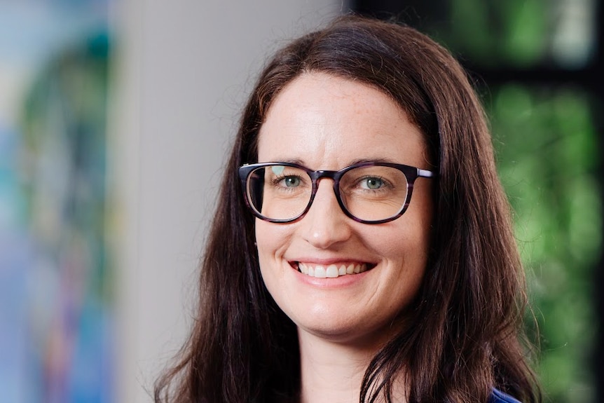 A woman wearing glasses and smiling.