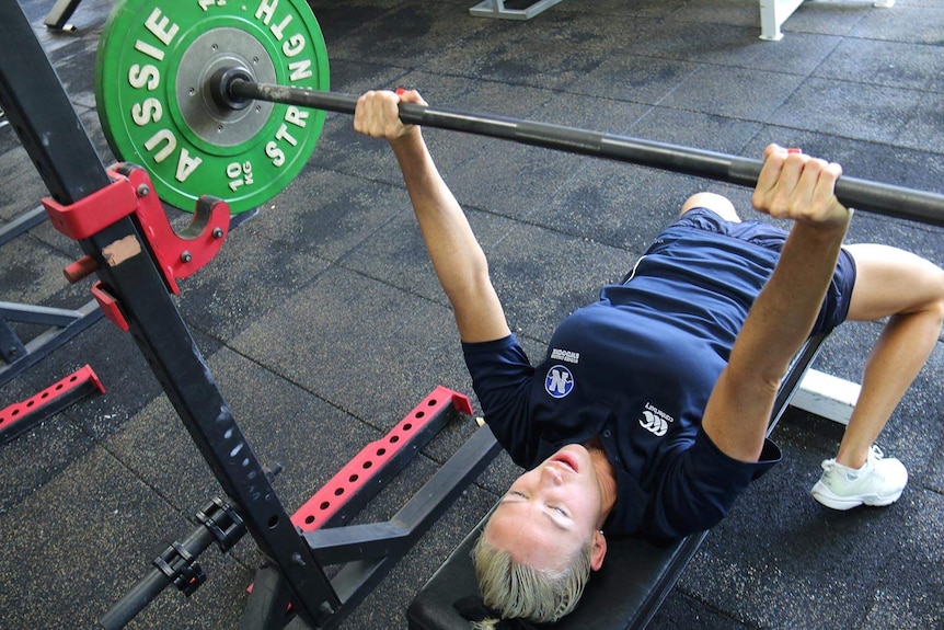 A woman bench pressing weights in a gym