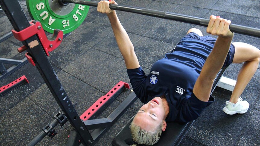 A woman bench pressing weights in a gym