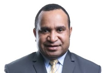 Papua New Guinean man Sam Koim in a professional work photo wearing a grey suit