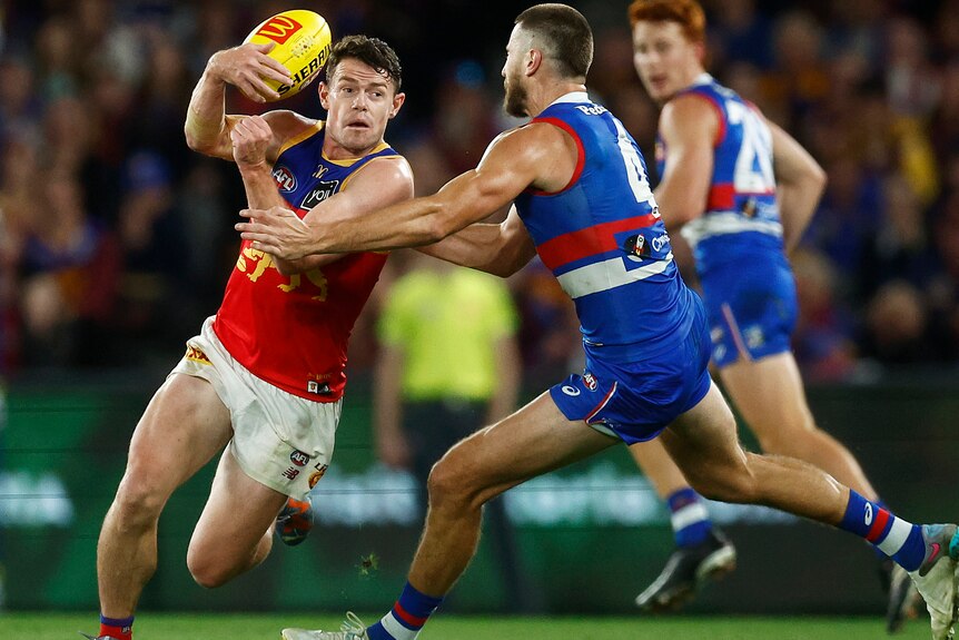Lachie Neale looks to handball as Marcus Bontempelli tries to tackle him