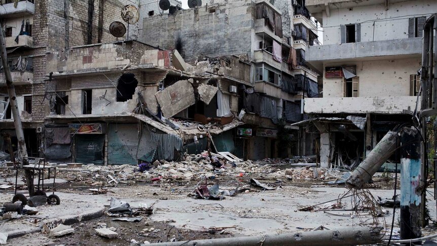 Debris litters the street in front of heavily damaged apartment buildings in Aleppo