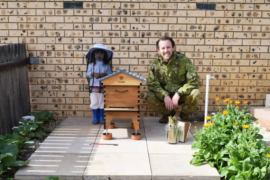 Mike Lewi and Dominique in their backyard standing near their hive.