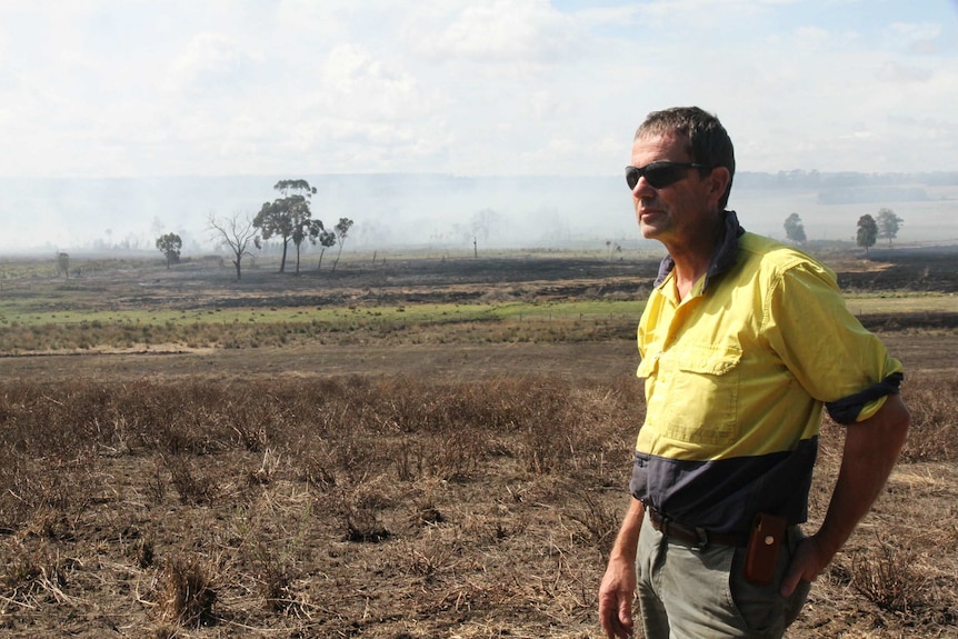 A farmer looks out at a peat swamp burning on his property.