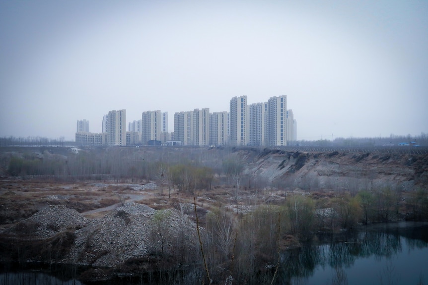 A group of apartment blocks in an open misty plain