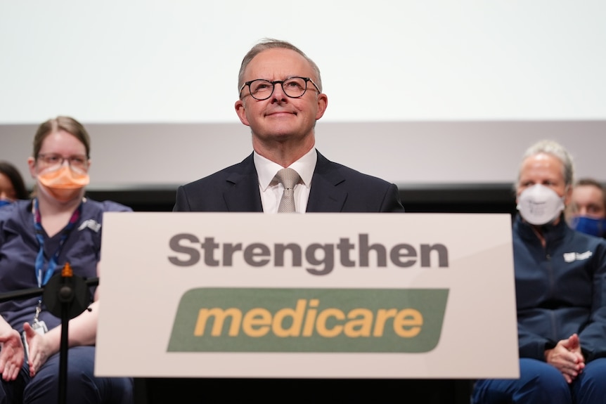 Anthony Albanese stands at a lecturn with "medicare" written on it