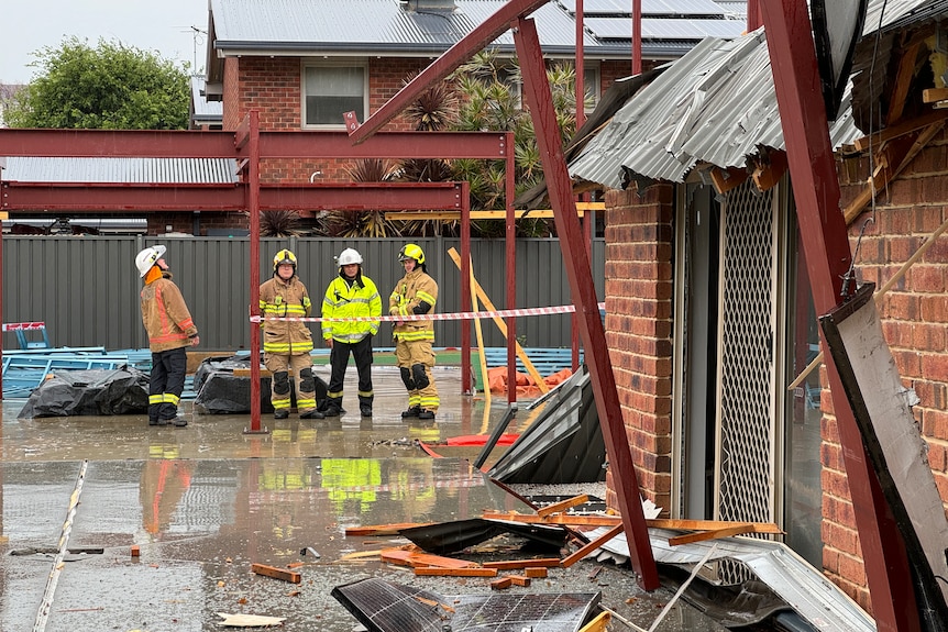 Emergency workers surveying damage to a house.