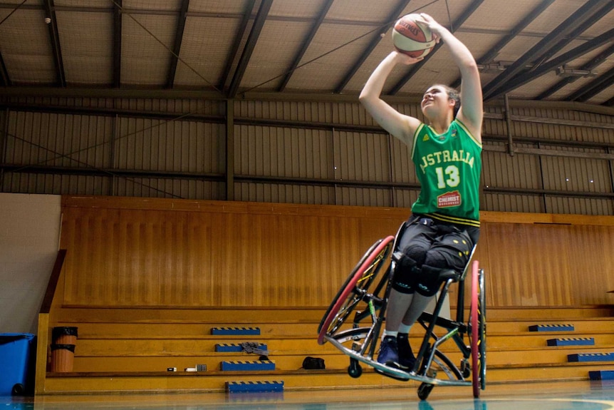 Annabelle Lindsay leans to one side of her chair and shoots towards a basketball hoop