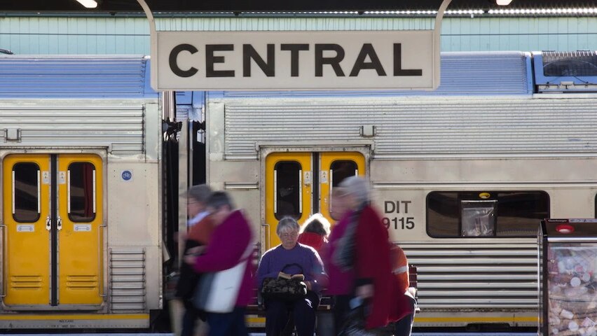 Elderly women sit in front of a parked train at Central Station Sydney