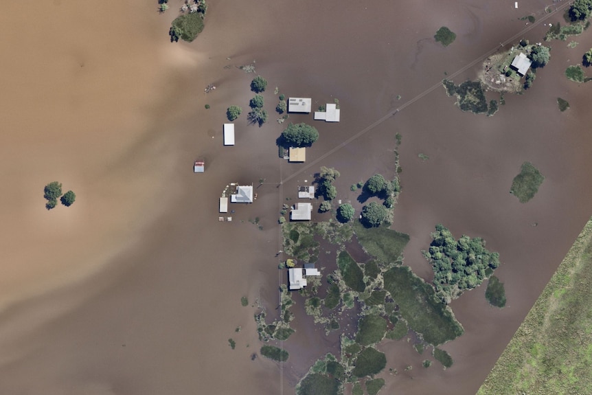 From above, the roofs of farmhouses poke through muddy floodwaters.