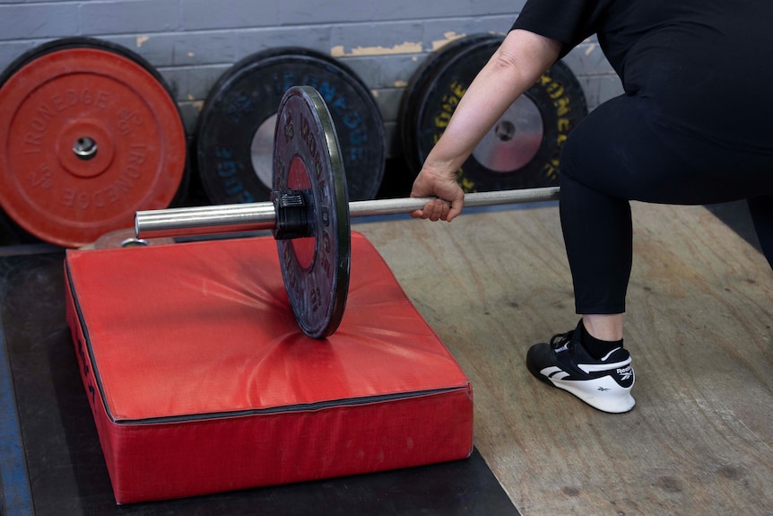 A close up of a weightlifting bar and a hand, ready to lift