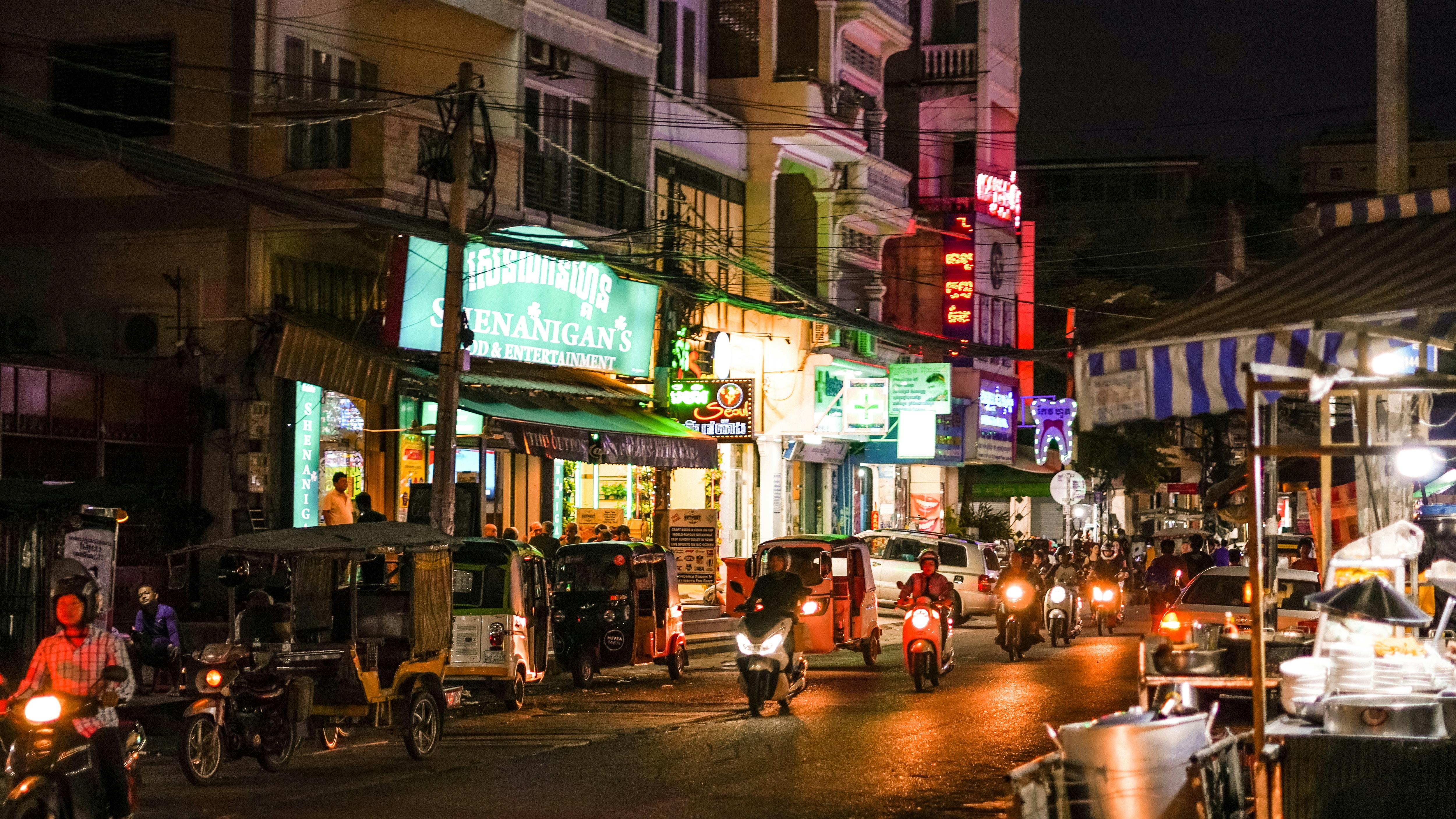 Asian city street at night with lights and motorbikes.