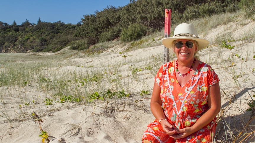 Volunteer Jenni Truman sits near one of the turtle nest markers on Frenchman's Beach on North Stradbroke Island.