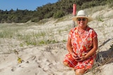 Volunteer Jenni Truman sits near one of the turtle nest markers on Frenchman's Beach on North Stradbroke Island.